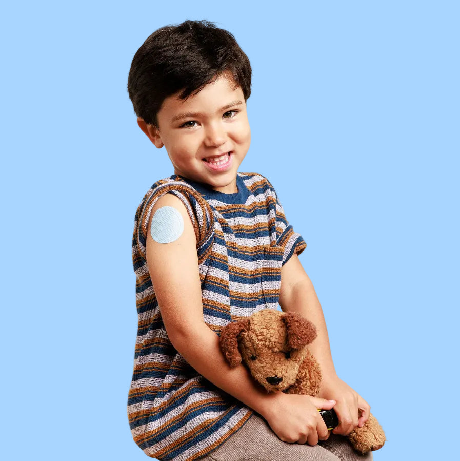 Smiling child with Thimble Prepare numbing patch on arm, holding a stuffed animal